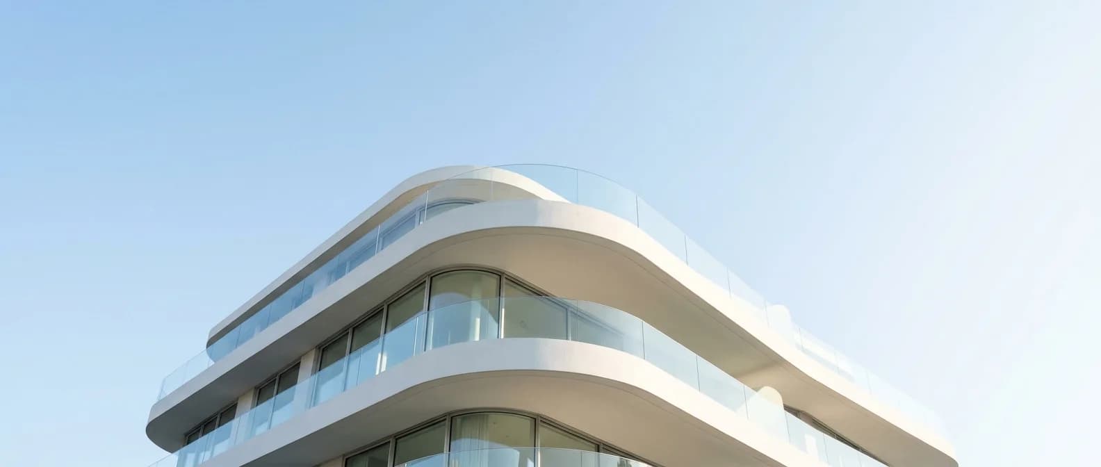 A modern white building facade against a clear morning sky